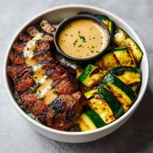 Grilled steak bowl with sauce and grilled zucchini served in a vibrant dish