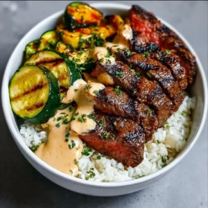 Grilled steak bowl featuring succulent steak, vibrant grilled zucchini, and savory sauce.