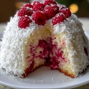 Raspberry Swirl Coconut Snowball Cake topped with fresh raspberries and coconut flakes