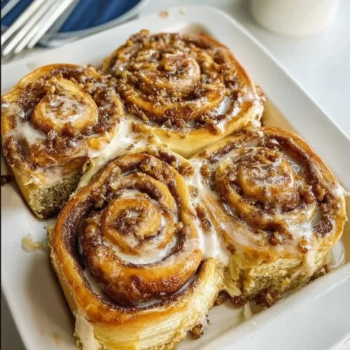 Banana bread cinnamon buns topped with glaze on a baking sheet
