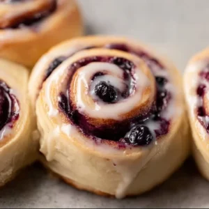 Delicious freshly baked blueberry cinnamon rolls with icing drizzle.