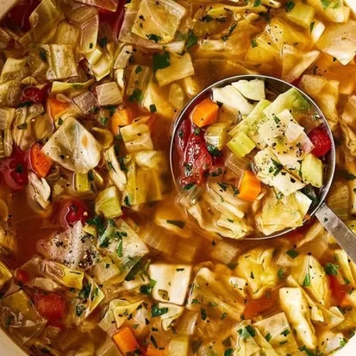 Bowl of healthy cabbage soup with fresh ingredients and herbs